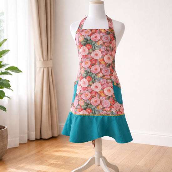Adult apron made from a floral print in shade of pink, yellow and blue, accented with teal at the bottom